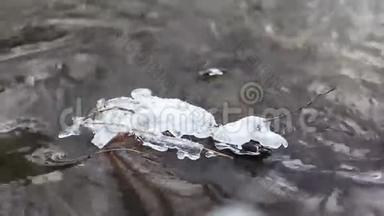 在一条湍急的泉水中，冰水的特写镜头。 冰在岩石上融化